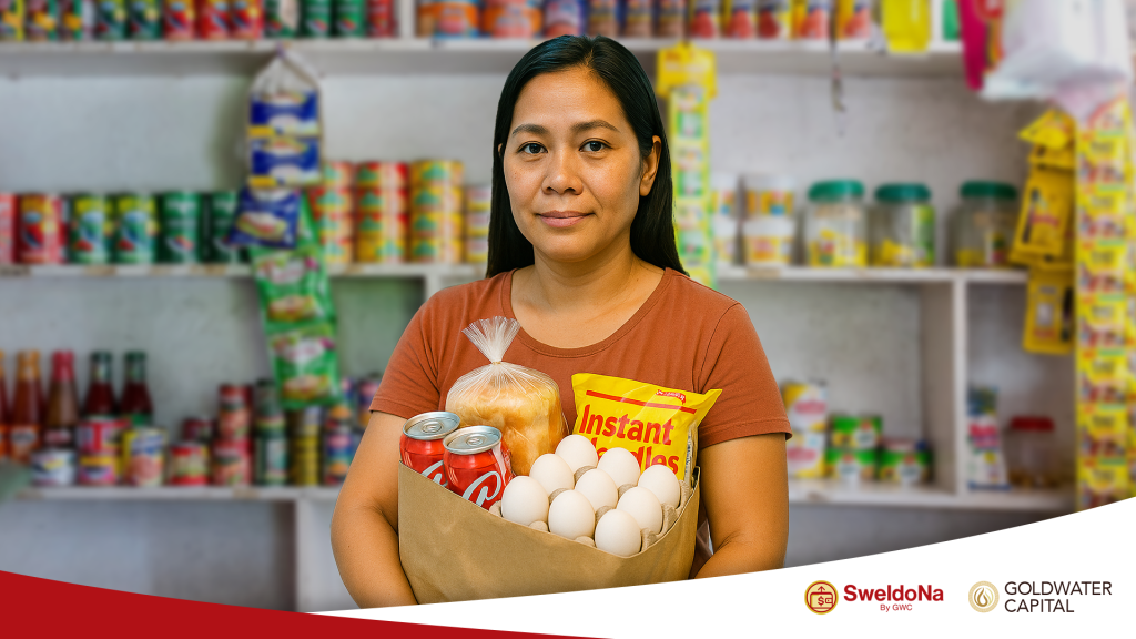 Ate Linda in front of her sari-sari store holding food items from her store.